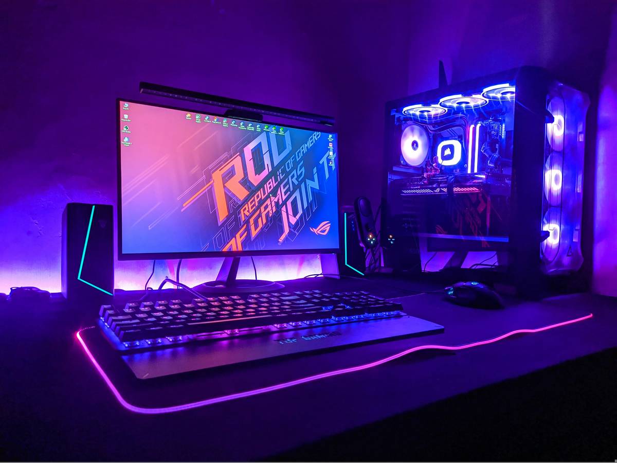 Gamer relaxing in ergonomic gaming bed frame with dual monitor setup and console storage underneath