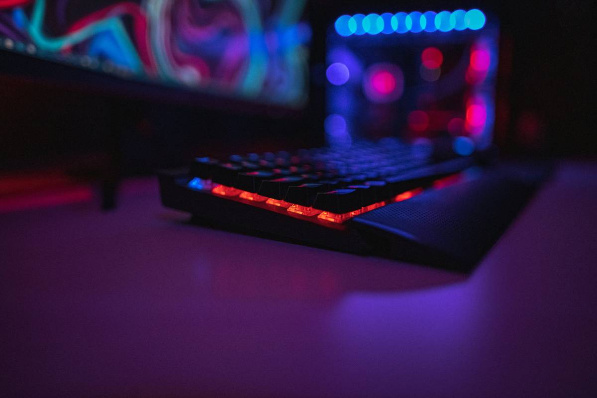 gaming room with queen bed featuring dual monitors, ambient lighting, and optimized furniture layout